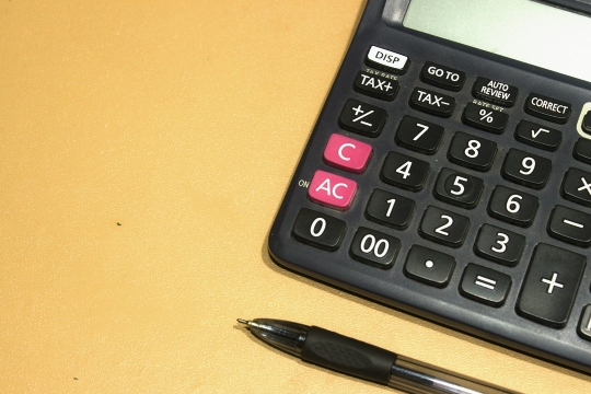 długopis i kalkulator na pomarańczowym tle
